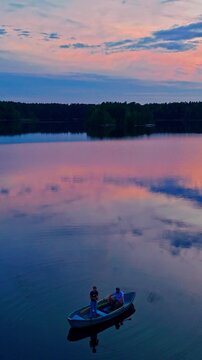 Vertical aerial view of father and son fishing in boat on Matildanjarvi lake Finland sunset