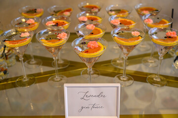 These elegant martini glasses are part of a display featuring cocktails garnished with vibrant pink edible flowers and citrus slices. © nedomacki