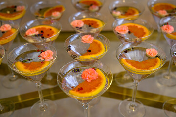 These elegant martini glasses are part of a display featuring cocktails garnished with vibrant pink edible flowers and citrus slices. © nedomacki