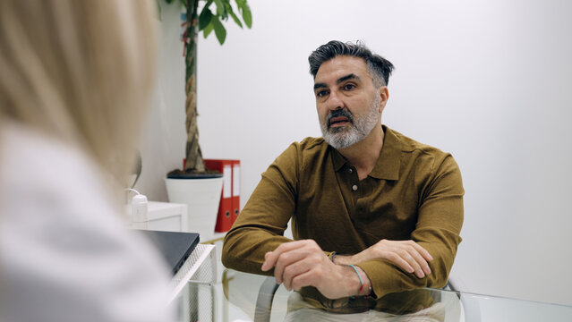 Mature man having medical consultation with a professional in a clinic, discussing health concerns and treatment options