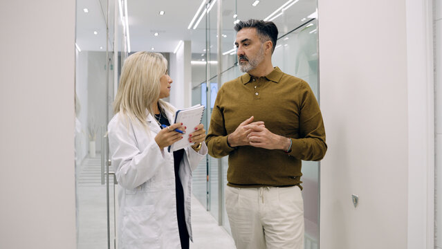 Medical professional consulting man about hair restoration in a modern clinic, offering advice and support for alopecia