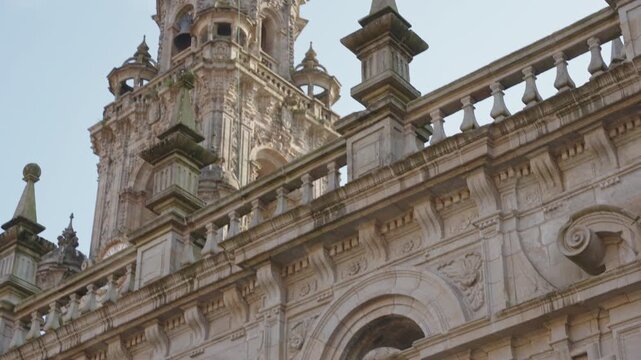 Close-up, detailed shot of an ornate stone facade featuring classical architectural carvings and niches housing stone statues of figures in historical attire.