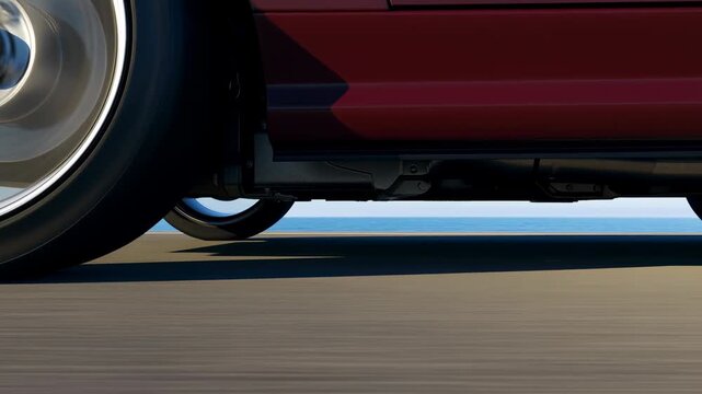 Red car moves along paved road in low-angle close side view as wheel spins beside glossy body panel, with blurred asphalt, bright daylight, and deep shadow beneath chassis
