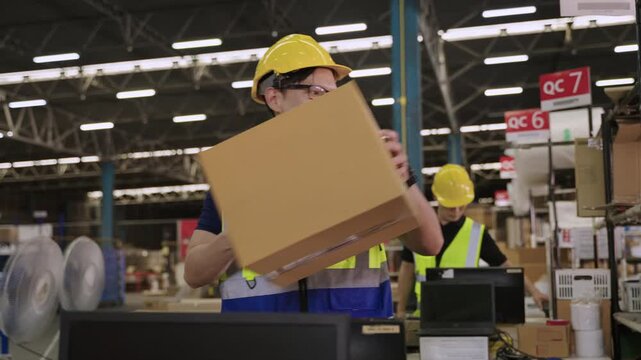 Team of Asian retail workers in uniform with yellow safety helmet using scanner for barcode scanning on cardboard box for stock and data with price before customer delivery in distribution warehouse. 