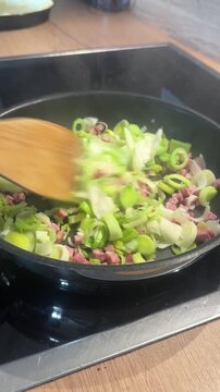 Diced bacon and sliced leeks sizzling in a pan on a home stove, evoking comforting homemade cooking, healthy meal preparation and cozy kitchen lifestyle