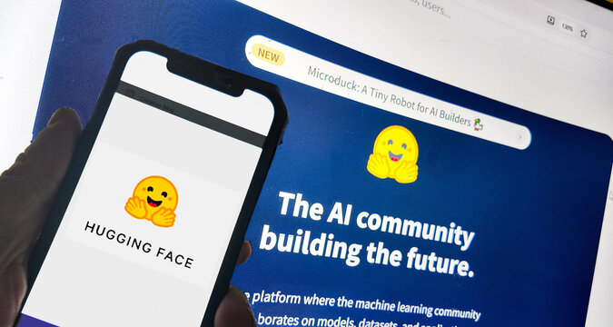 a computer screen with hugging face website displayed and a smart phone with the logo... Hugging Face is a central hub and community platform for artificial intelligence and machine learning