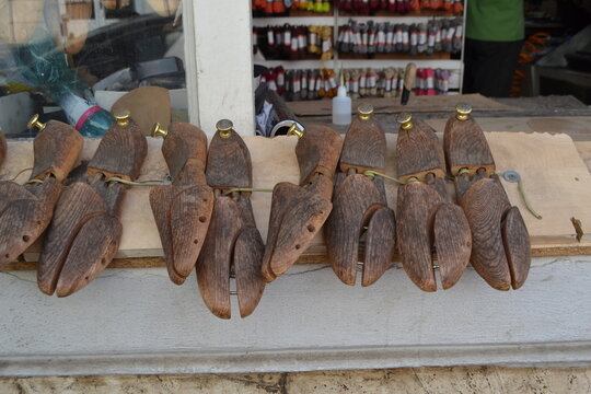 Multiple wooden shoe lasts lined on a board at a cobbler shop counter for craft display and leather repair background