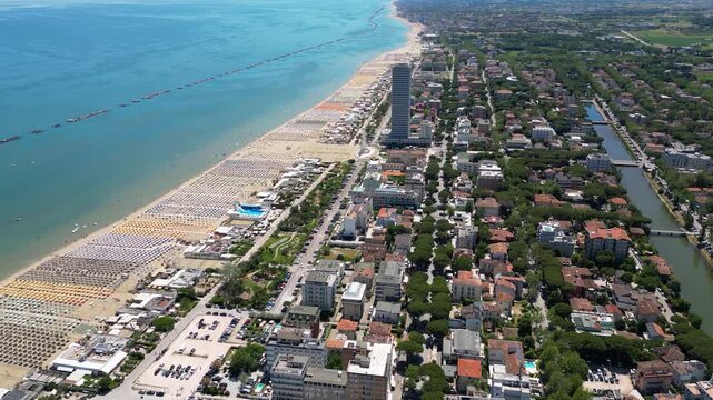 Aerial view of Cesenatico skyscraper and sandy beach lined with colorful umbrellas in Riviera Romagnola, Adriatic Sea, Emilia-Romagna, Italy