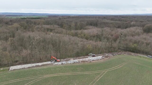 Construction against polder flooding flood taming land wall site field area stabilization project drone aerial wooded area agricultural. Tracked excavator constructed roadside earth embankment large