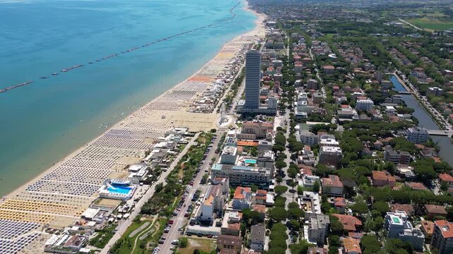 Aerial view of Cesenatico skyscraper and sandy beach lined with colorful umbrellas in Riviera Romagnola, Adriatic Sea, Emilia-Romagna, Italy