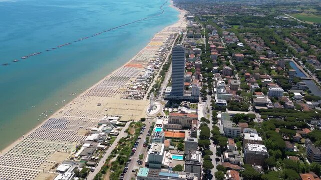 Aerial view of Cesenatico skyscraper and sandy beach lined with colorful umbrellas in Riviera Romagnola, Adriatic Sea, Emilia-Romagna, Italy