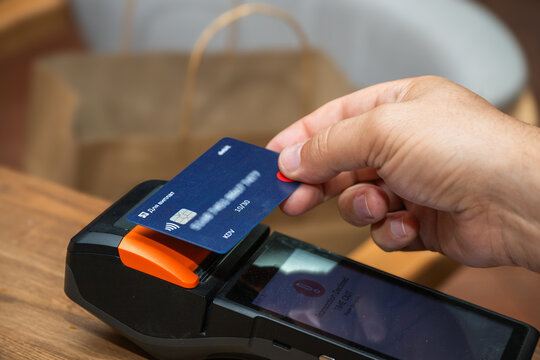 A hand places a blue contactless payment card onto a POS terminal showing a transaction declined timeout message on its screen.