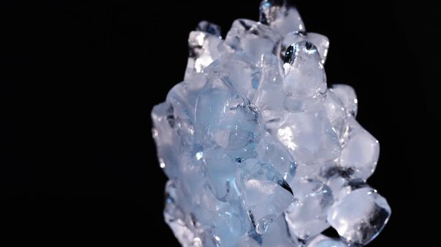 Slow moving melting ice pile with dripping water on black background for drink cooling, refreshment visuals and abstract design