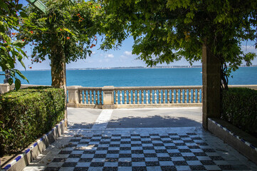 Sea view through garden archway with checkered floor © Oksana