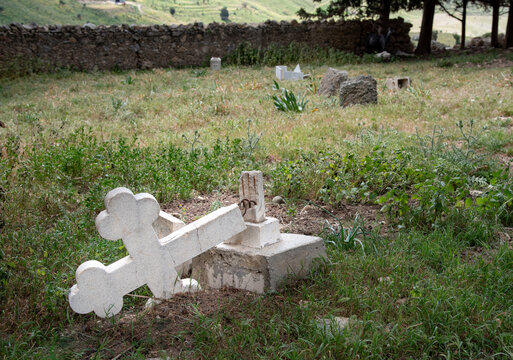 Broken white marble cross laying on the ground in a cemetery, evoking themes of loss, remembrance, and the passage of time