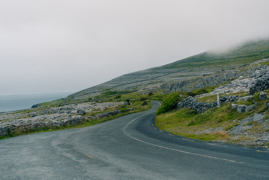 The Burren, County Clare, Ireland - August 23, 2026. Unique limestone landscape characterized by rugged rock formations, exposed limestone pavements, green fields, and dramatic scenery along the Atlan