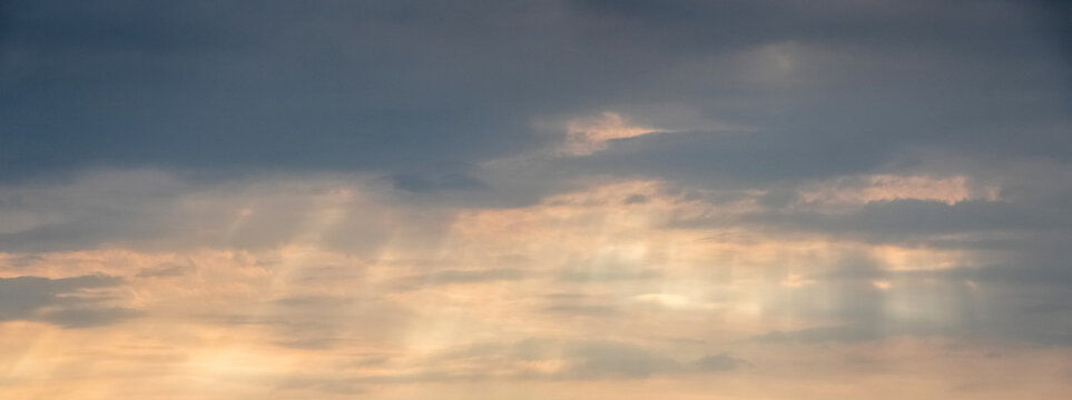Cloudy sky with sun rays through clouds at dawn panoramic view