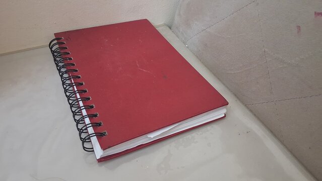 Vibrant red spiral notebook rests on a clean light desk surface