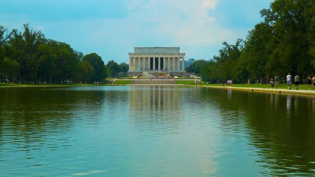Epic Wide Slow Motion Shot Of Lincoln Memorial And Reflecting Pool With Strolling Tourists Under Summer Clouds