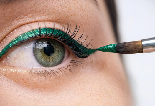 Green metallic eyeliner application macro photo, close up woman eye makeup cosmetics brush, creative beauty portrait for salon tutorial