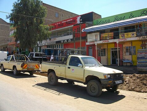 NAROK, KENYA - 27 JANVIER 2010: Camionnettes pick-up Toyota gar&eacute;es au bord d'une rue commer&ccedil;ante anim&eacute;e au Kenya.