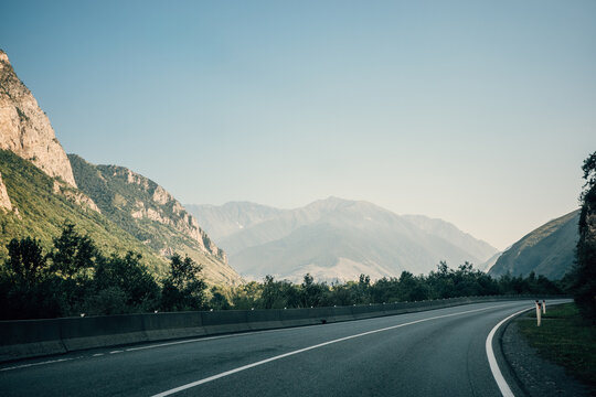 Georgia scenic mountain road through Caucasus valley, empty highway curve inviting road trip, tourism, adventure travel, freedom, nature and summer exploration.