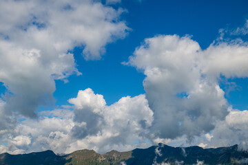 Towering white summer clouds drift above a rugged alpine mountain ridge near Hinterburgseeli in the Swiss Alps. © Andrei Tomas