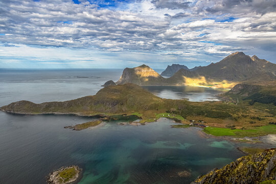 Dramatische Luftaufnahme der Lofoten-K&uuml;ste mit schroffen Bergen, t&uuml;rkisfarbenem Meer und gr&uuml;ner Landschaft vom Offers&oslash;ykammen, Lofoten, Norwegen, Europa