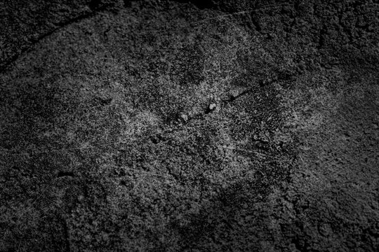 Full frame and top view of abstract black or dark grey concrete surface with rough grainy texture and vignette borders