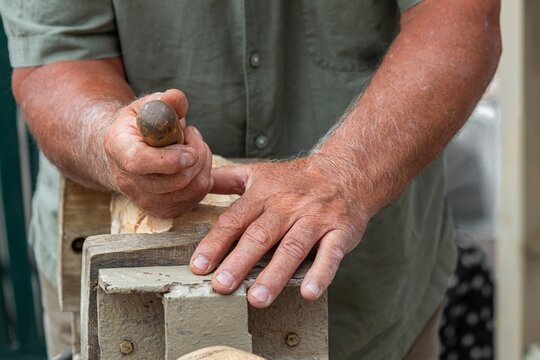 Craftsman hand-carving wooden figure with chisel on workbench