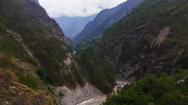 Rasuwagadhi, Nepal - 29 August 2026: Aerial view of Trishuli River flowing through a deep mountain valley with steep forested slopes and rocky cliffs under a cloudy sky.