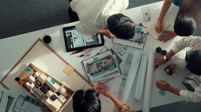 Top down aerial view of architect engineer team writing sticky notes and sticking note at house model while interior designer talking and discussing about building exterior designing. Alimentation.