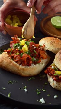 Authentic Mexican al pastor sandwich preparation with chopped pineapple topping