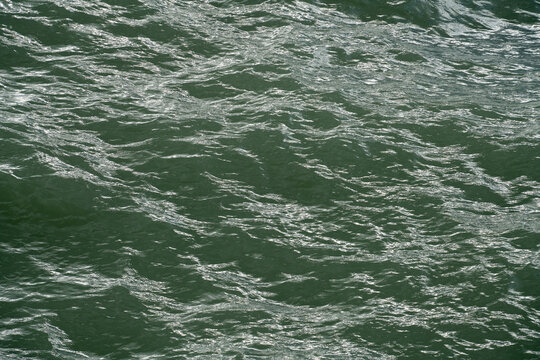 Water moves gently under the sunlight with small ripples forming and fading away
