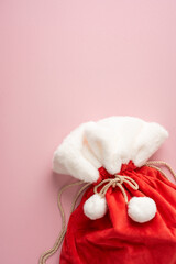 Naklejka premium Red Santa gift sack with plush trim for Merry Christmas and Happy New Year celebrations on vertical pastel pink background