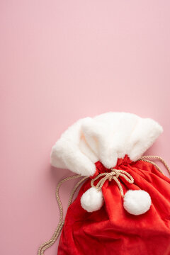 Red Santa gift sack with plush trim for Merry Christmas and Happy New Year celebrations on vertical pastel pink background
