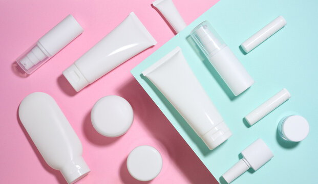 A set of white cosmetic packaging, creams, tubes, and bottles on a colored background.