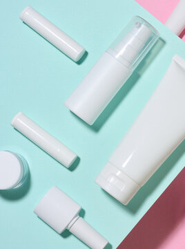 A set of white cosmetic packaging, creams, tubes, and bottles on a colored background.