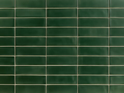 Dark green glossy ceramic subway tiles with a brick pattern layout, modern interior wall cladding texture