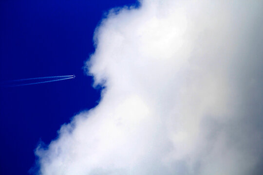 An airplane streaks across a brilliant blue sky