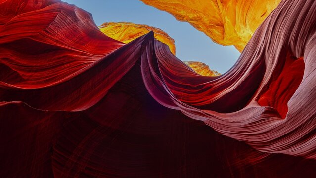 Slot canyon with flowing red sandstone walls and a view toward the sky.