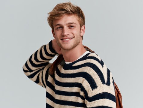Portrait of a handsome young man with blonde hair wearing a striped sweater smiling at the camera