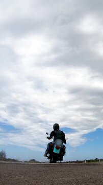Vertical slow motion view of a biker riding away on a custom motorcycle as it enters a rural road, with natural engine sounds and a cinematic motorcycle travel atmosphere.