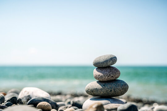 Balanced stone stack on a pebble beach with a blurred ocean background 