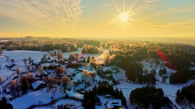 Aerial view of a snowy forest landscape with small houses illuminated by the golden hour sun in Latvia.