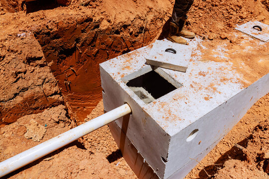 Workers prepare concrete septic tank in ground at construction site