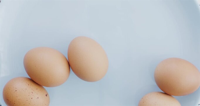 Raw eggs. Protein and nutrition. Farming. Brown raw chicken eggs on a blue plate. Healthy food.	