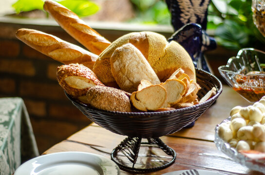 Assortment of fresh breads in a basket on a rustic wooden table