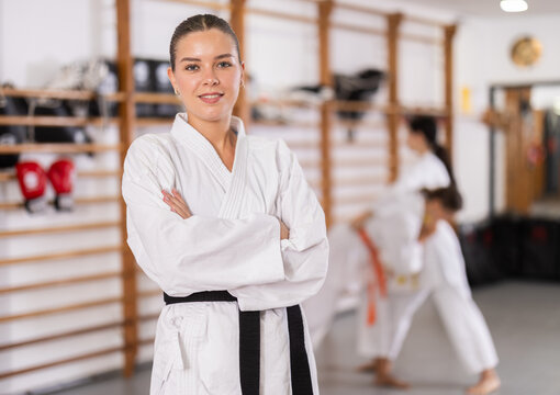 Positive young girl wearing kimono standing in sports hall during workout session