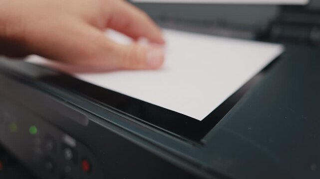 Office worker placing paper into scanner of multifunction printer